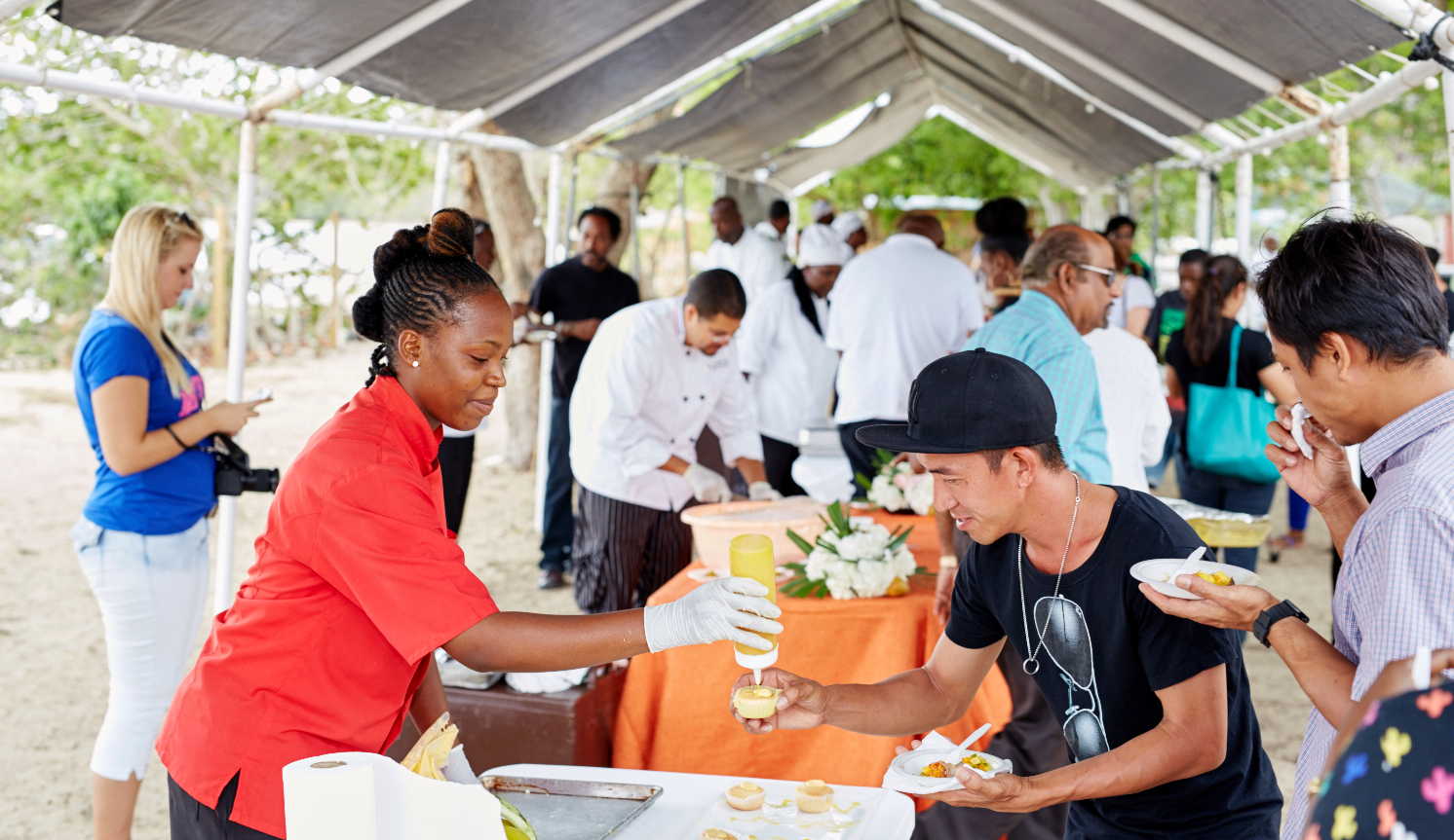 A chef serves a fresh mango drink to a visitor at a Nevis Mango Festival food tasting