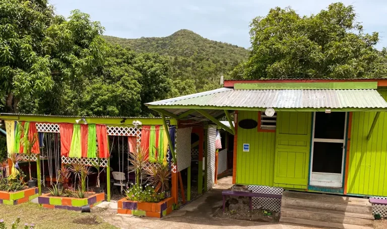 The brightly painted exterior of Passion Bar and Grill in Cox Village, Nevis, with green hills behind