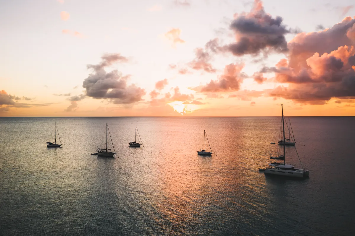 Sailboats at anchor off the west coast of Nevis as the sun sets over the Caribbean Sea