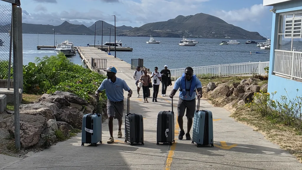 Crew wheeling guests' suitcases up from Oualie Pier in Nevis after a private water-taxi crossing from St. Kitts