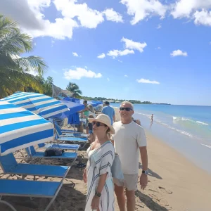 Cruise guests beside the striped loungers and umbrellas at Ganzies on Pinney's Beach, Nevis