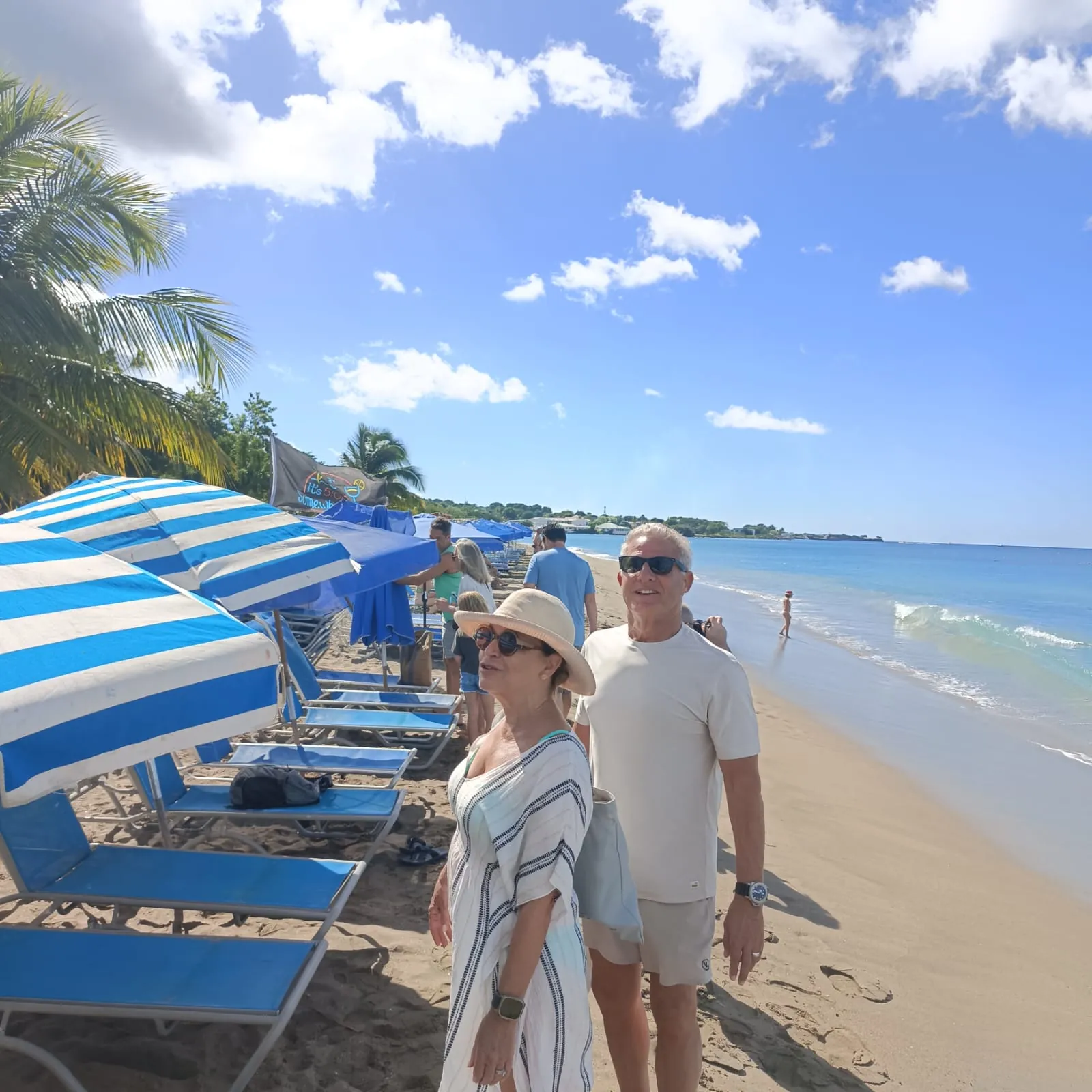 Cruise guests beside the striped loungers and umbrellas at Ganzies on Pinney's Beach, Nevis